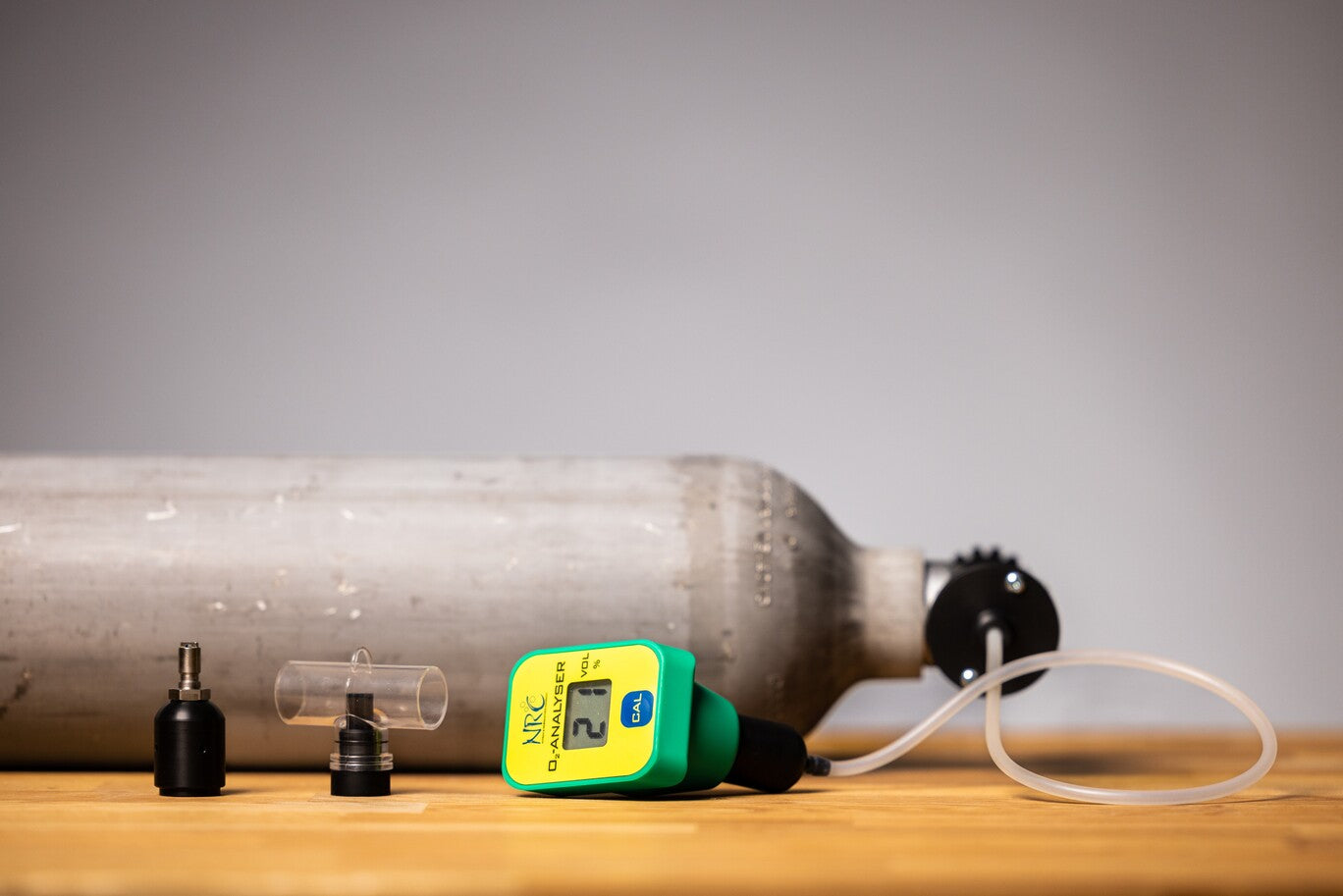 NRC oxygen analyzer with calibration accessories next to a scuba cylinder, used for verifying oxygen content in diving gas mixes