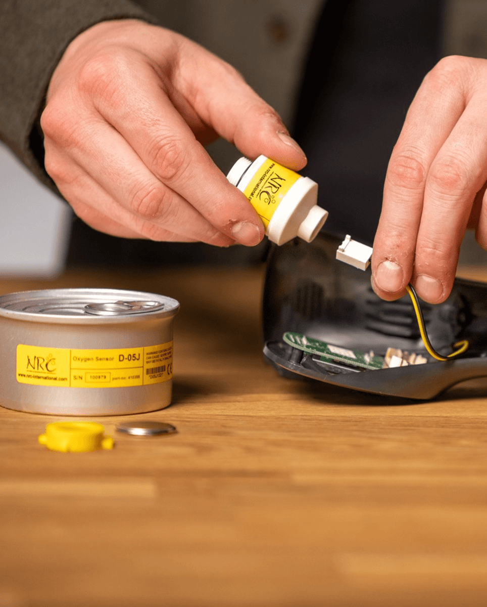 Installing an NRC oxygen sensor into a gas analysis device, showing the sensor unit, wiring connector, and packaging on the workbench.